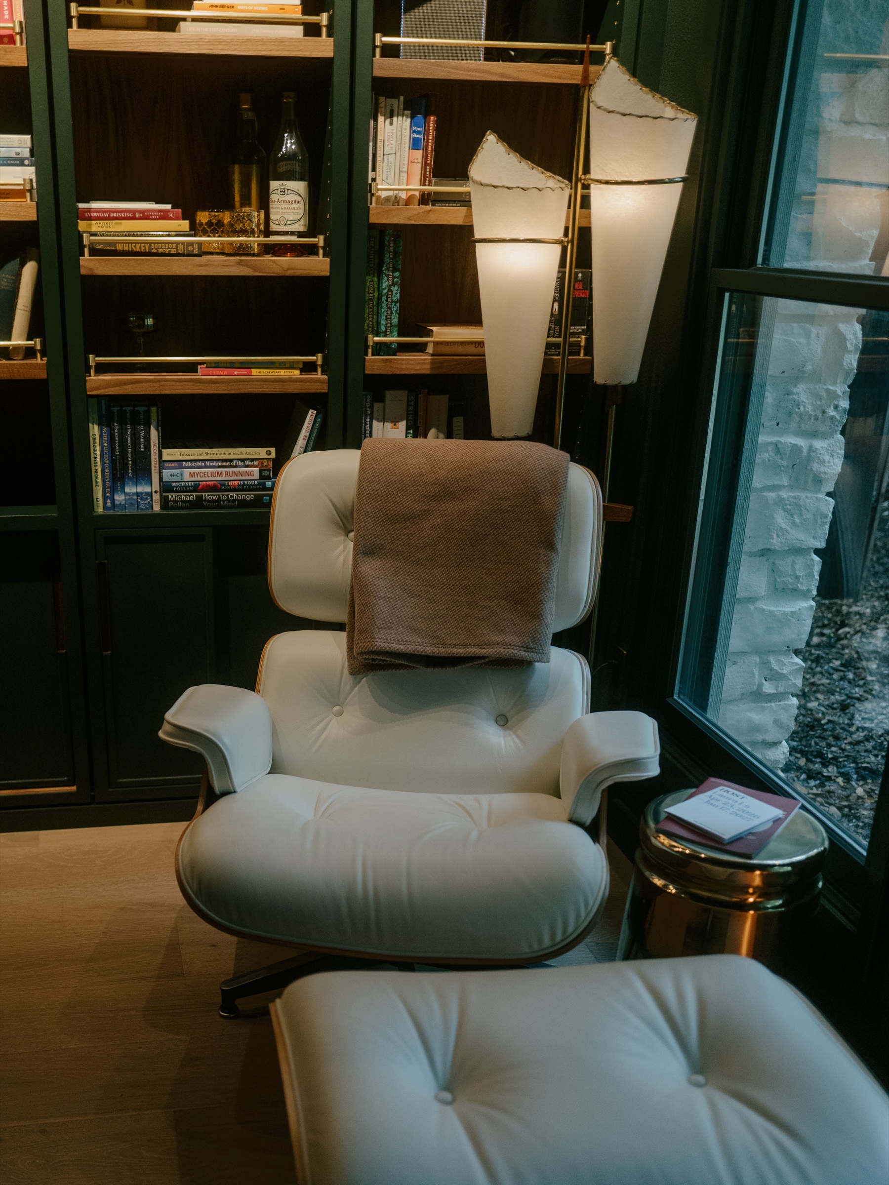 A white lounge chair and ottoman beside a paper floor lamp